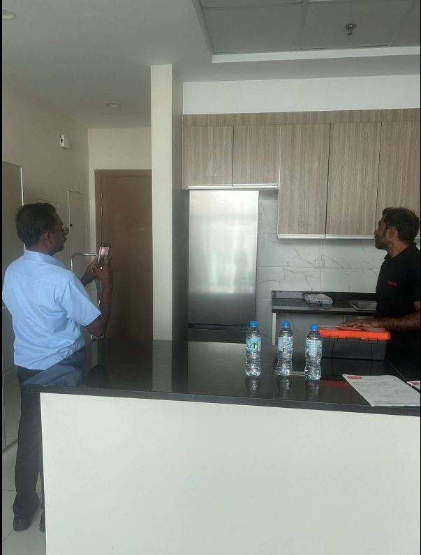 Customer explaining an appliance fault to a 24x7 Customer Care technician in a Dubai kitchen
