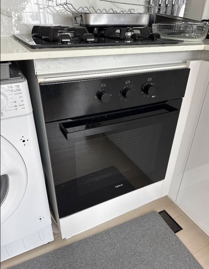 Built-in oven and gas hob repaired next to a washing machine in a Sharjah kitchen