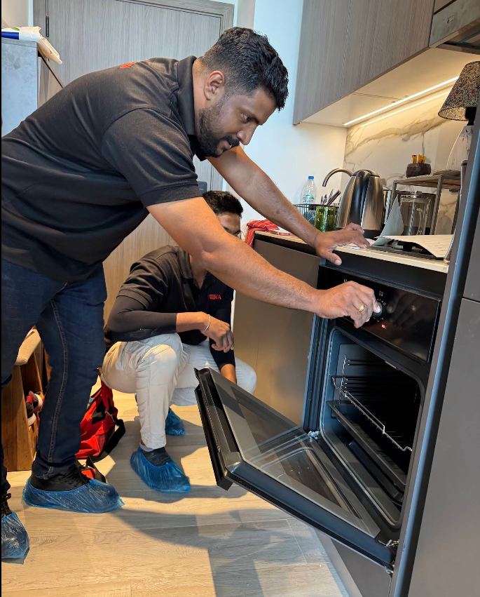 Technician repairing a built-in electric oven in a modern Dubai kitchen