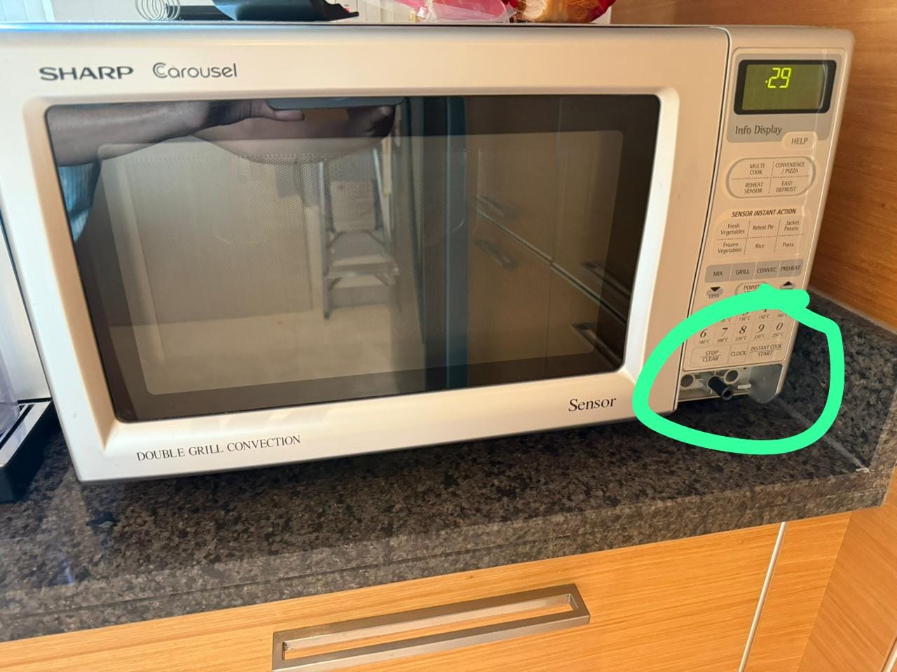 Countertop microwave with the door latch area marked as the reported fault
