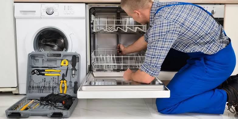 Dishwasher pulled out with a full technician toolkit on the kitchen floor