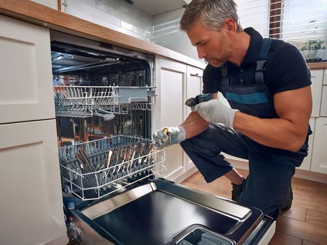 Technician servicing the spray arms and filter of a built-in dishwasher