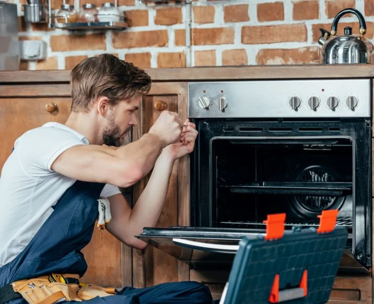 Technician repairing an electric stove and oven in a kitchen