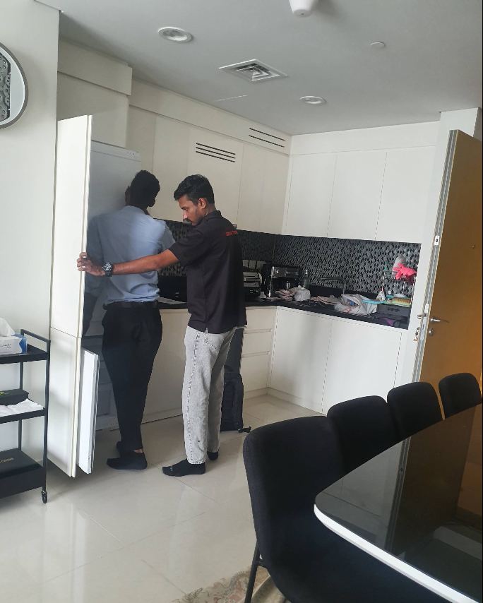 Technicians servicing an integrated fridge freezer in a Dubai apartment kitchen