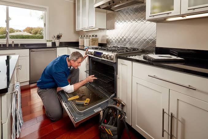 Technician inspecting a gas cooking range oven cavity