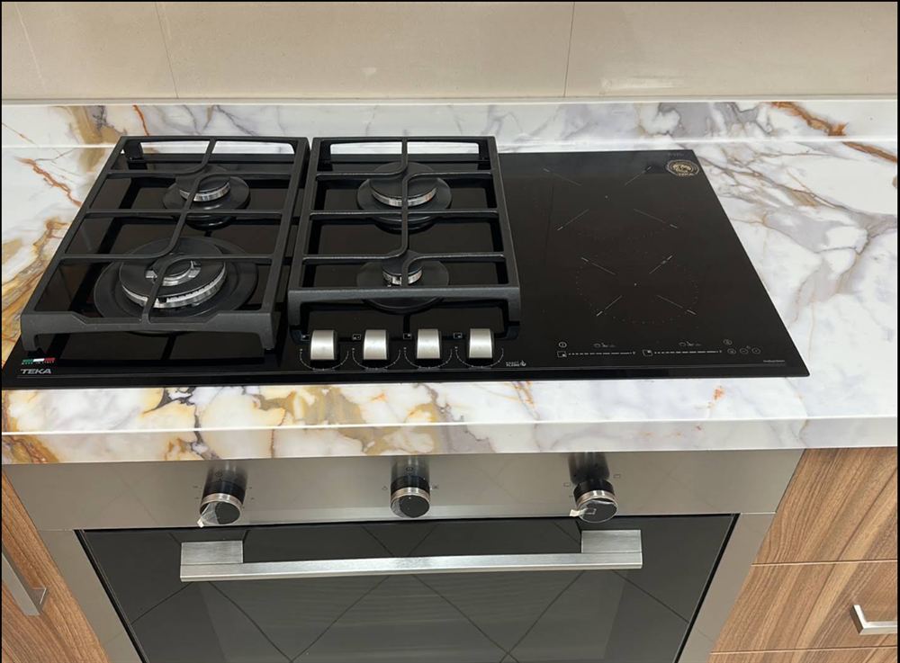 Gas hob and induction cooktop serviced on a marble kitchen counter in Dubai