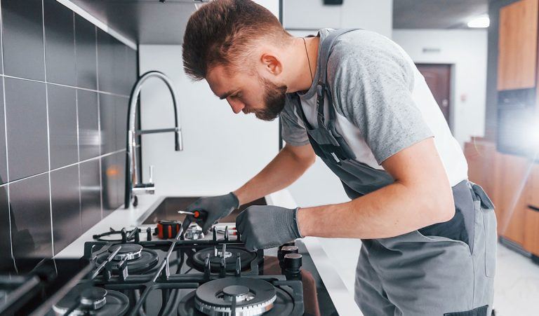 Technician servicing gas hob burners and jets in a Dubai kitchen