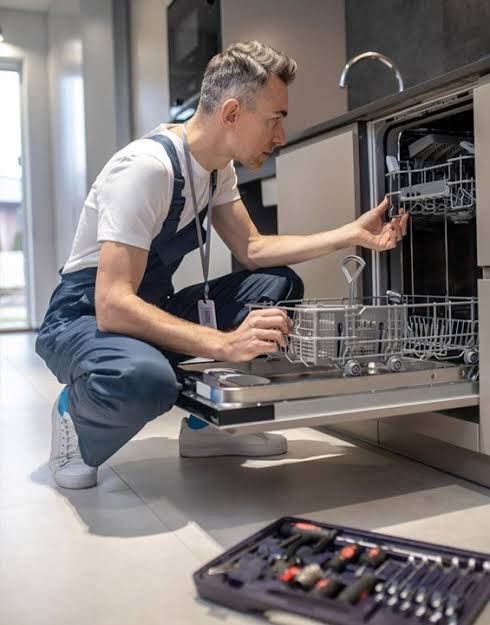 Technician servicing an integrated dishwasher in a modern UAE kitchen