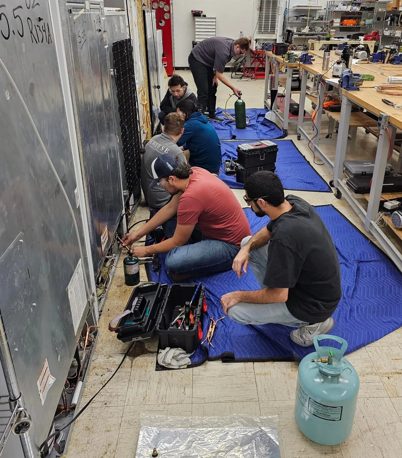 Refrigeration technicians brazing and charging sealed systems in our workshop