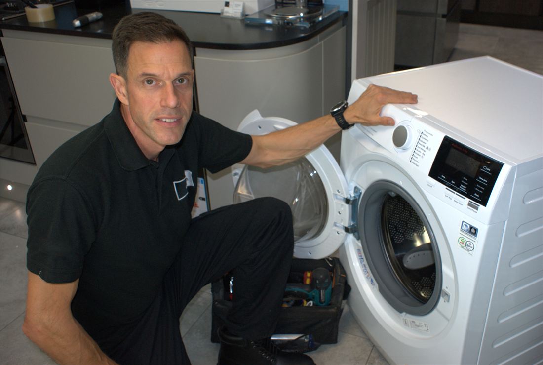 Technician beside a fully repaired and tested washing machine
