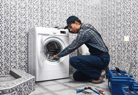 Technician servicing a washing machine in a Sharjah apartment